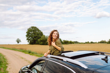 Beautiful woman enjoying nature, looking out of the windows car while having a road trip. Lifestyle, travel, tourism, nature, active life.