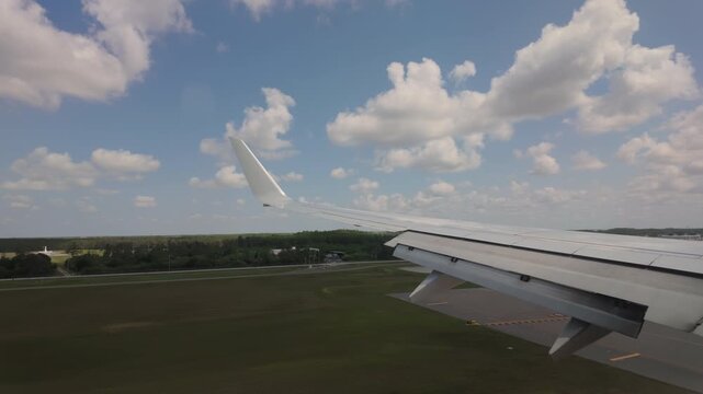  Air plane landing in runway. Wide view of the wing from the porthole. Fort Myers RSW