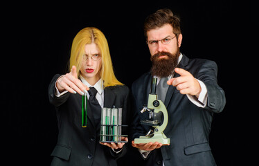 Chemistry lesson. Students in university laboratory with test tubes and microscope. Science, chemistry, technology, biology concept. Male and female researcher pointing to you. Scientific experiments.