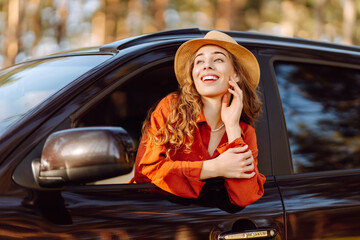 Young woman leaning out of the car window enjoying nature. Road trips summer holidays.