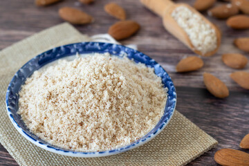 Homemade almond flour made with raw nuts on wooden table. Close-up. Selctive focus. Healthy gluten-free alternative for baking and cooking.