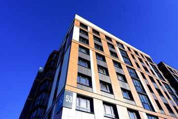 Fototapeta premium Building exterior on blue sky. New house, home complex. Facade building background. Modern building, houses with glass windows. New Buildings architecture. European residential apartment. Condominium