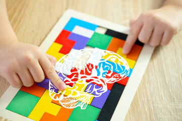 Toddler's hands manipulate colorful wooden geometric pieces intellectual puzzle, smart child solves...