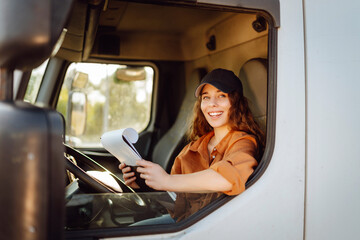 Young woman professional truck driver sitting and driving big truck cross country. Transport...
