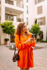 Fototapeta premium Young woman tourist walking on city street using smartphone mobile phone. Communication with friends.Blogging.