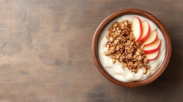 Wooden bowl filled with creamy yogurt topped with sliced apples and granola, warm morning light, high-angle shot, minimalist style, healthy breakfast concept.