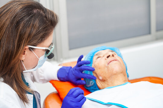 Dermatologist carrying out a skin biopsy on the face of a senior adult patient