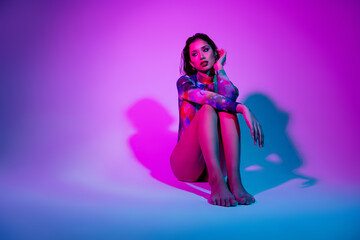Photo of shy thoughtful woman dressed print bodysuit sit floor empty space isolated violet color background