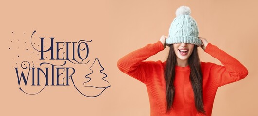 Happy young woman in warm clothes on beige background. Hello, winter