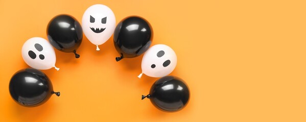 Many funny Halloween balloons on orange background with space for text, top view