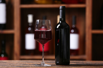 Bottle and glass of red wine on table in cellar
