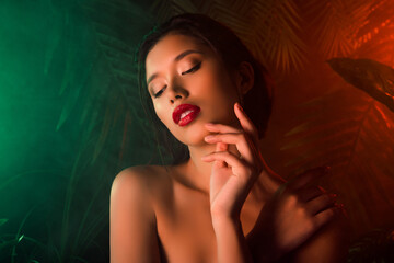 Portrait of stunning model girl hand fingers touch smooth face skin neon light smoke jungle plants...