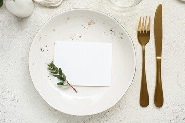 Plate with gold cutlery and blank card on white grunge background
