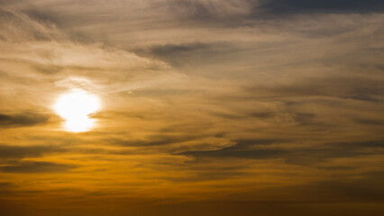Sunset sky and the sun setting in thin clouds