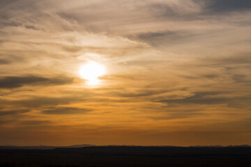 Sunset sky and the sun setting in thin clouds