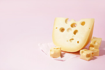 Baking paper with pieces of Swiss cheese on pink background