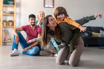 A diverse family group relaxes in a cozy living room setting, smiling parents and grandparents...