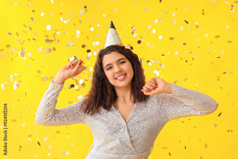 Canvas Prints beautiful young woman with party whistle and confetti celebrating birthday on yellow background