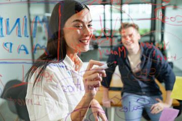 Professional business team brainstorming and working together about marketing project. Female caucasian leader writing idea on stick note while coworker present her idea confidently. Immaculate.