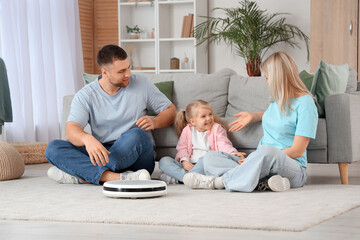 Happy family with robot vacuum cleaner sitting on carpet at home