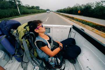 Asian girl hitchhiking in a pickup truck in latin america