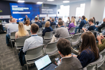 Business professionals attending a conference session with a panel discussion in progress. Diverse...