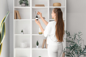 Beautiful young woman with aroma diffuser at home