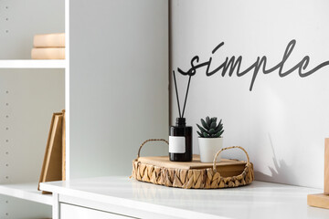 Aroma diffuser, houseplant in wicker tray on table and text SIMPLE on wall in room