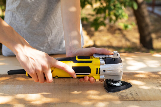 Carpenter Sanding A Wood Plank Outdoors Using An Electric Sander For Furniture