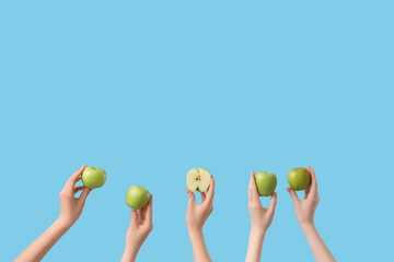 Hands holding fresh apples on blue background