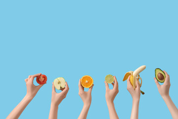 Hands holding cut fruits and vegetables on blue background