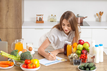 Young woman with healthy food making meal plan in kitchen. Diet concept