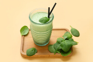 Glass of fresh spinach smoothie on yellow background
