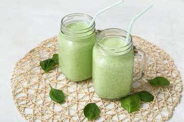 Mason jars of fresh spinach smoothie on white background