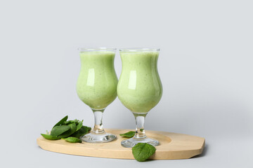 Glasses of fresh spinach smoothie on grey background
