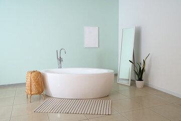 Interior of bathroom with bathtub, mirror and plant