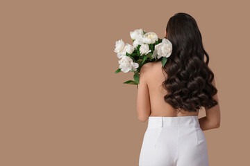 Young woman with bouquet of white peony flowers on brown background, back view