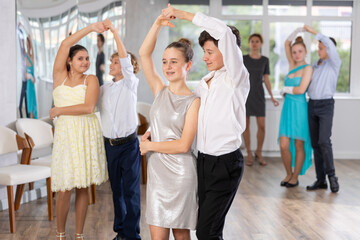 Positive teen boy and girl are dancing classic version of waltz in couple during lesson at studio....