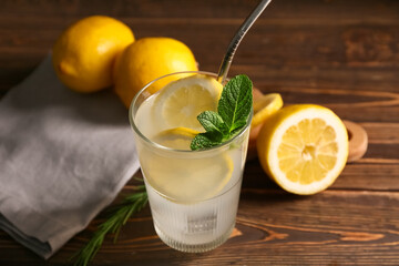 Glass of fresh lemonade with mint and rosemary on wooden background