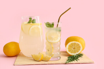 Fototapeta premium Glass and jug of fresh lemonade with mint on pink background