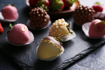 Board with chocolate covered strawberries on black background, closeup