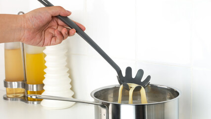 Closeup of a person steering a cooking pot of pasta.