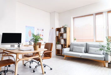 Interior of medical office with doctor's workplace, sofa and shelf unit
