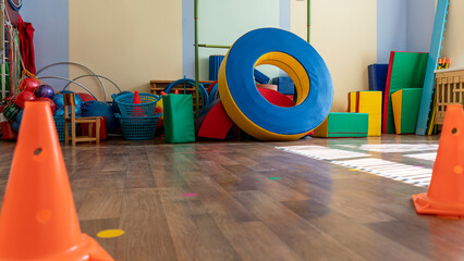 Brightly colored gymnasium with various soft play equipment including foam blocks, large rings and...