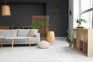 Cozy sofa, pouf, lamp and decor with palm branches