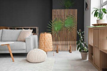 Cozy sofa, pouf, lamp and decor with palm branches