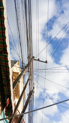 Tulungagung, Indonesia October 09, 2024: tangled cables, electric poles filled with tangled cables with a clear sky background. Electric cables or internet lines in Tulungagung City.