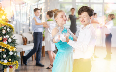 Couples dancing - teenagers in festive clothes dance the Viennese waltz near the Christmas tree