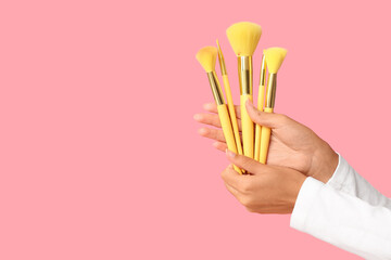 Female hand with different brushes on pink background