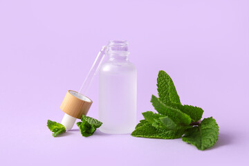 Bottle of essential oil and mint leaves on lilac background, closeup